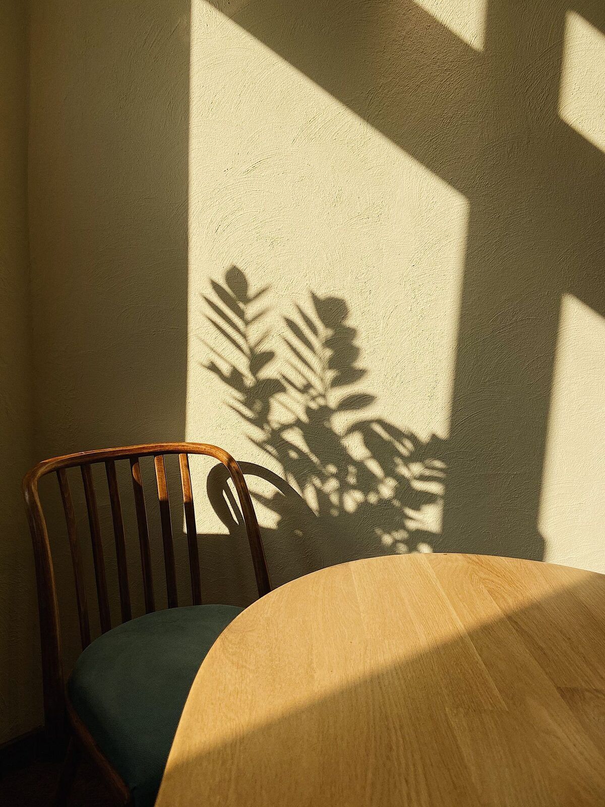 Rincón del estudio con una silla de madera junto a una mesa, iluminado por luz natural de tarde