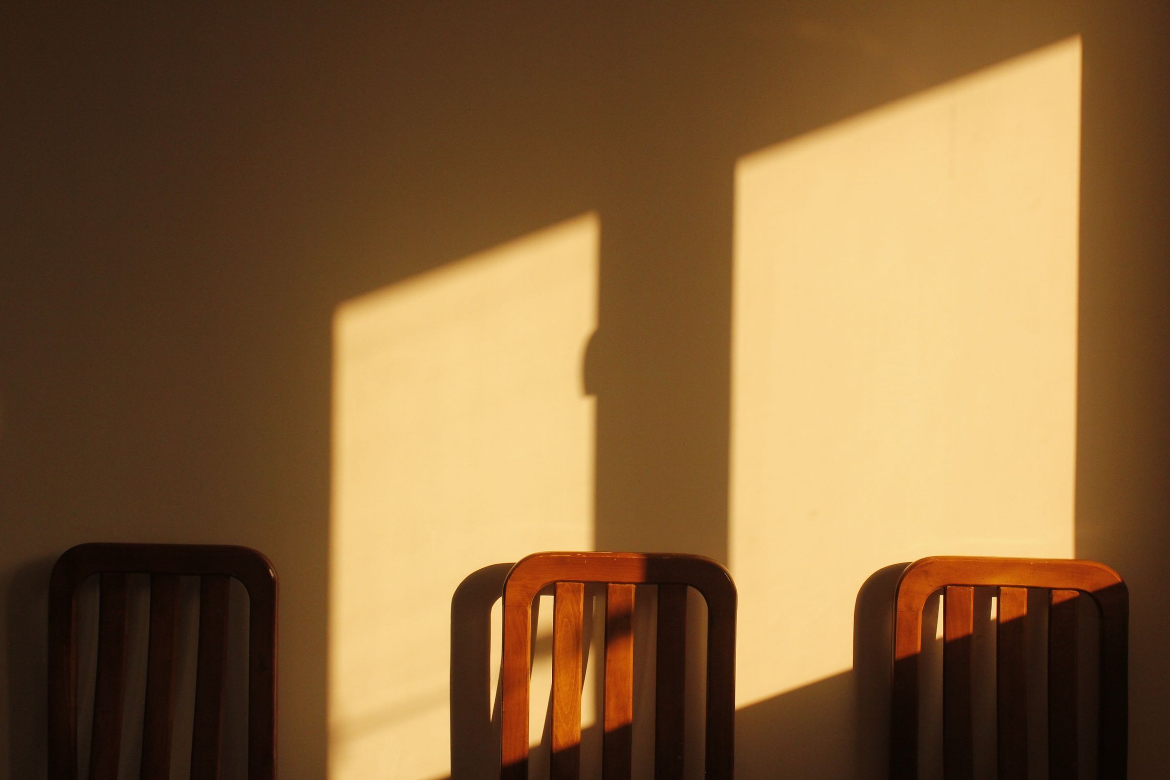 Sala de espera del estudio con sillas de madera contra una pared bañada por luz de tarde